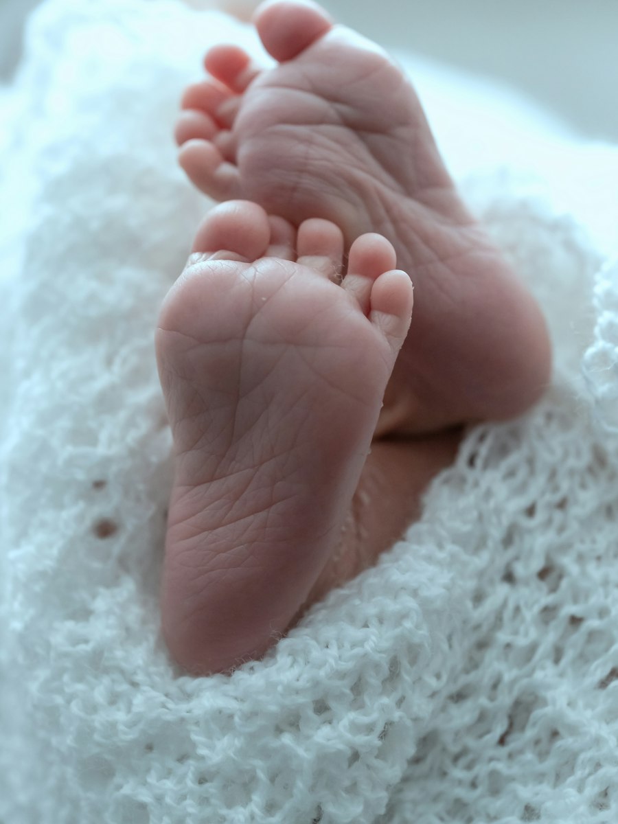 A newborn baby's feet resting on a soft white knit blanket